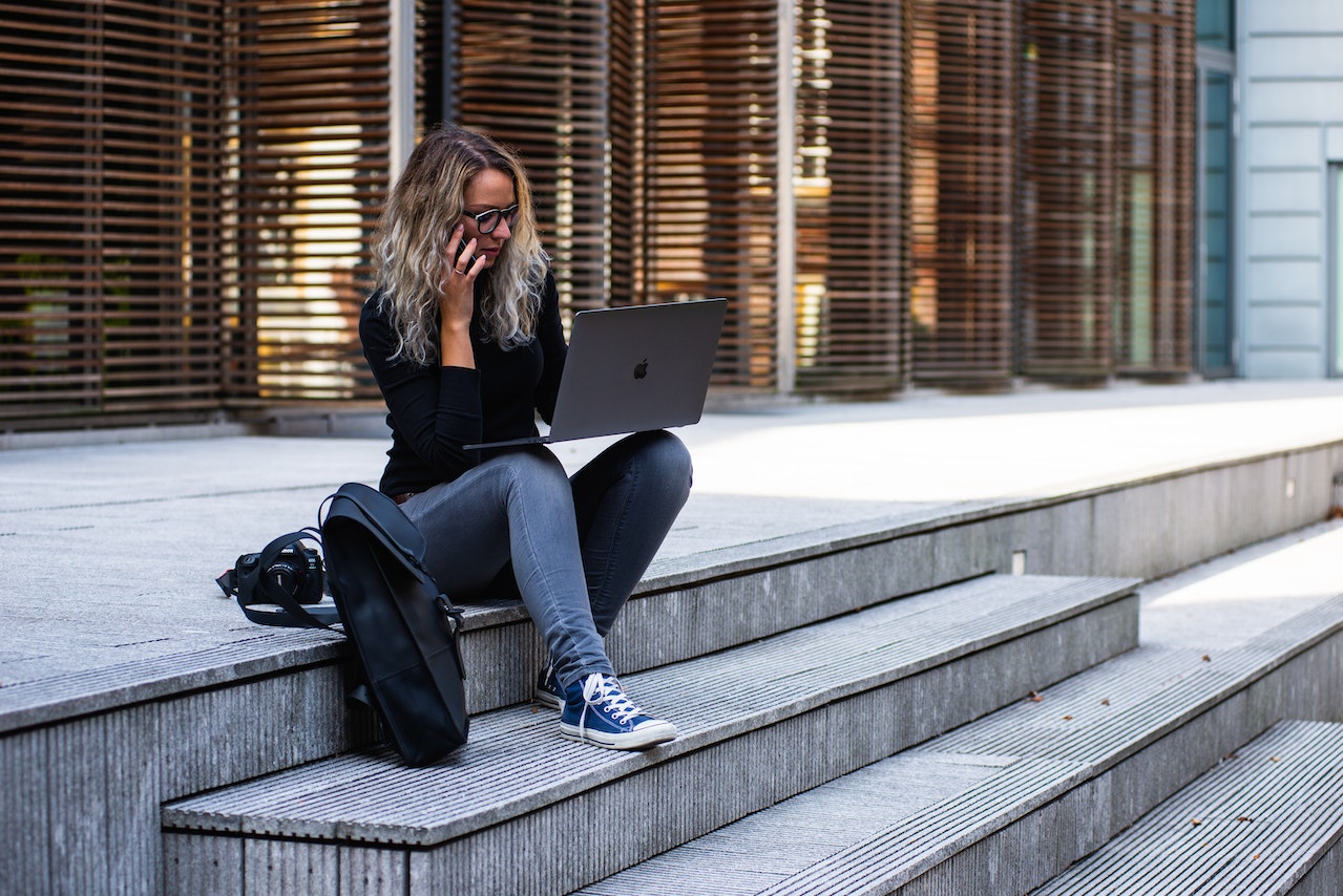 millennial woman using laptop outside