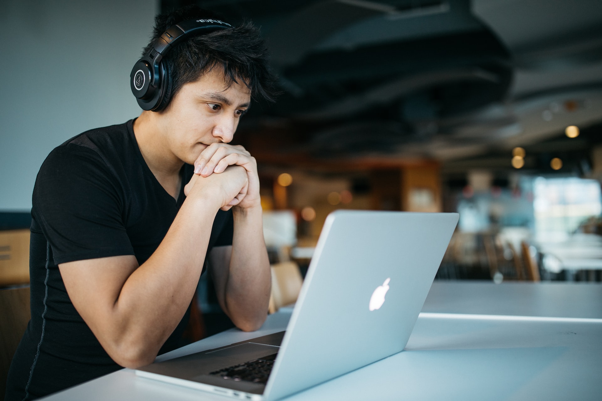 man wearing headphones looking intently at laptop