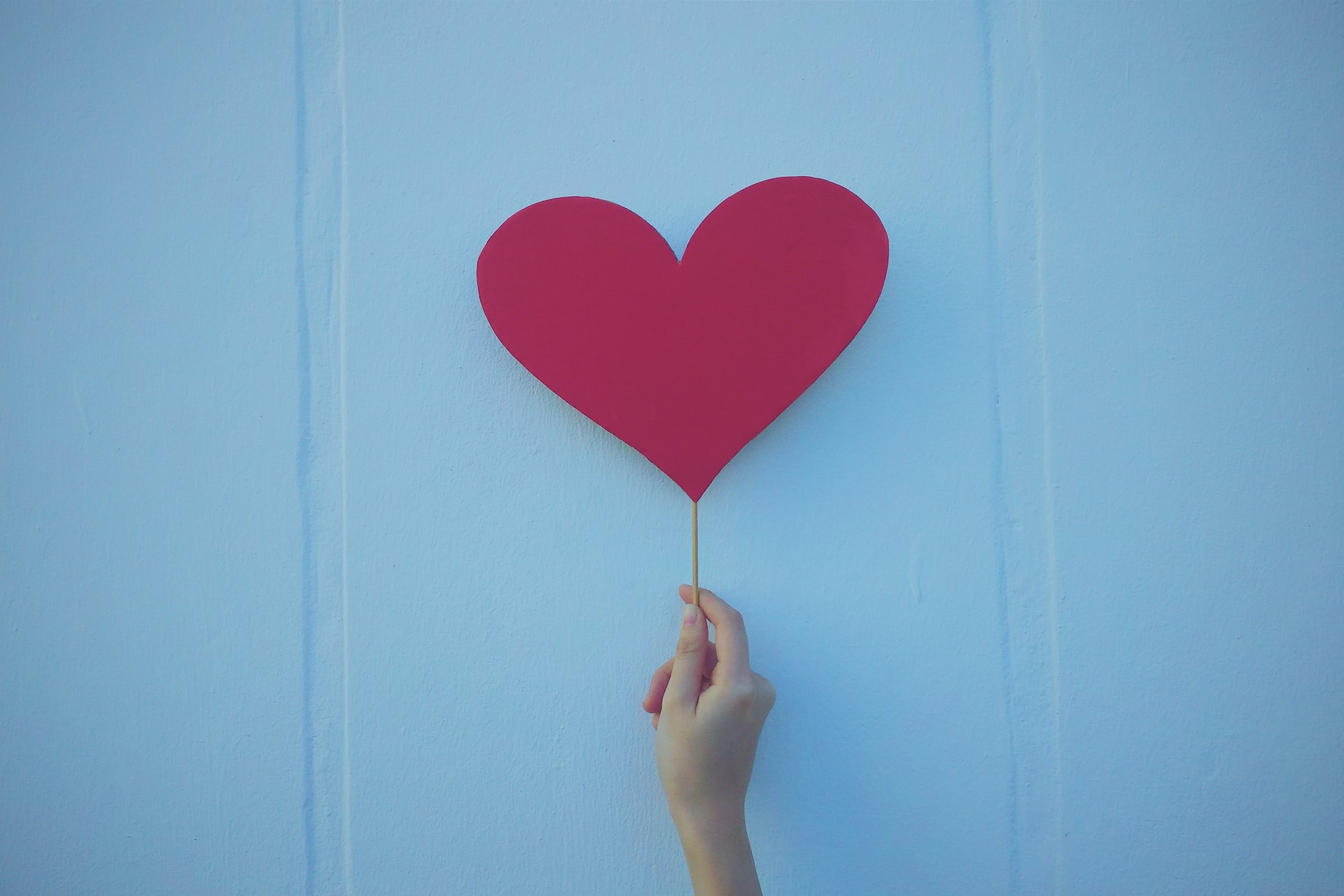 hand holding paper heart on stick