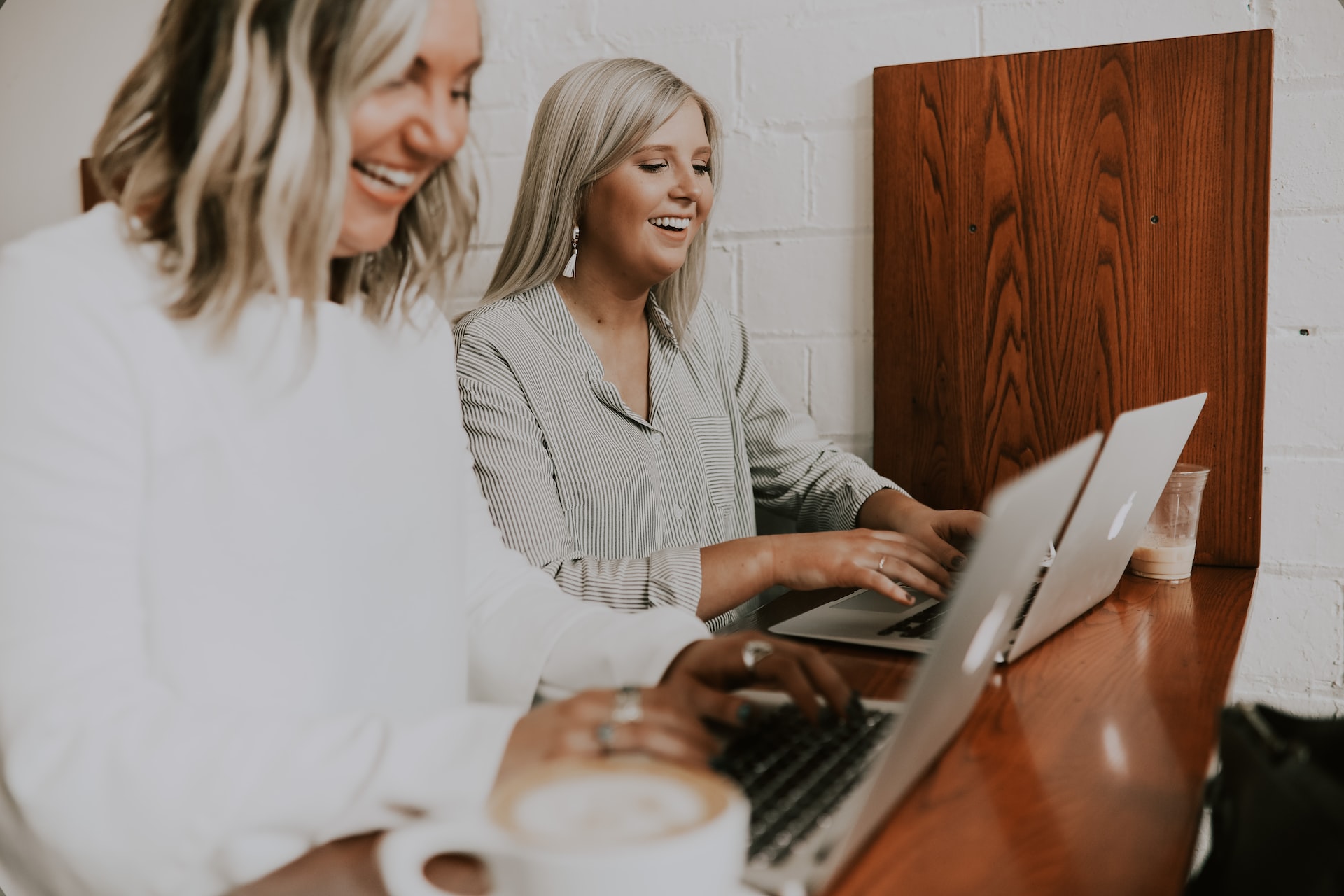two smiling women using laptops