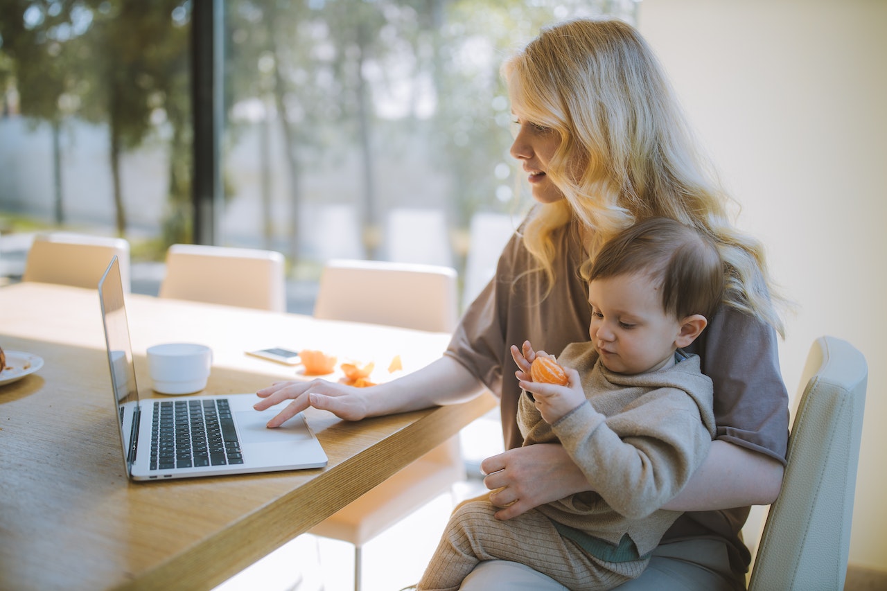 woman working from home while holding baby
