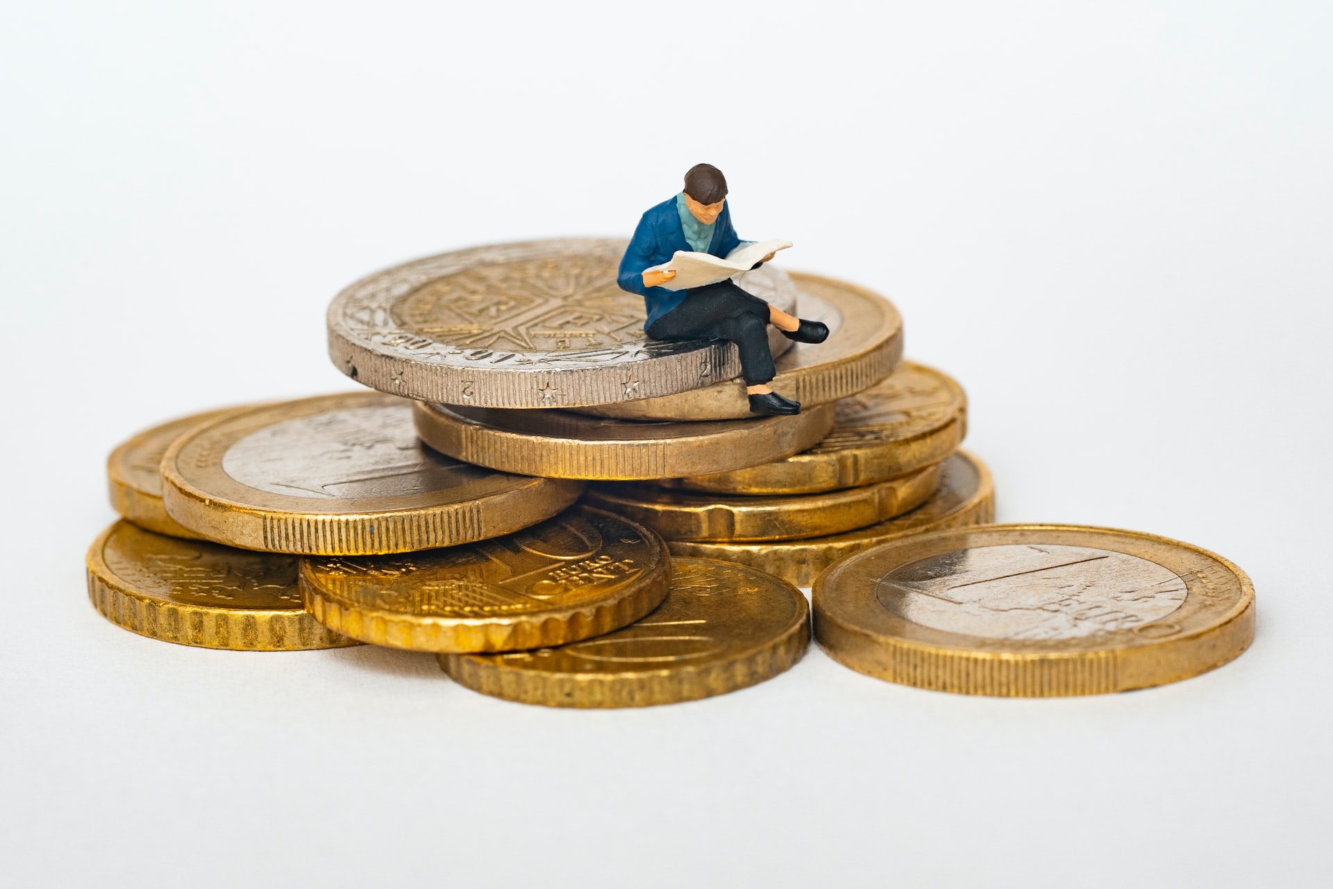 model man sitting on stack of coins