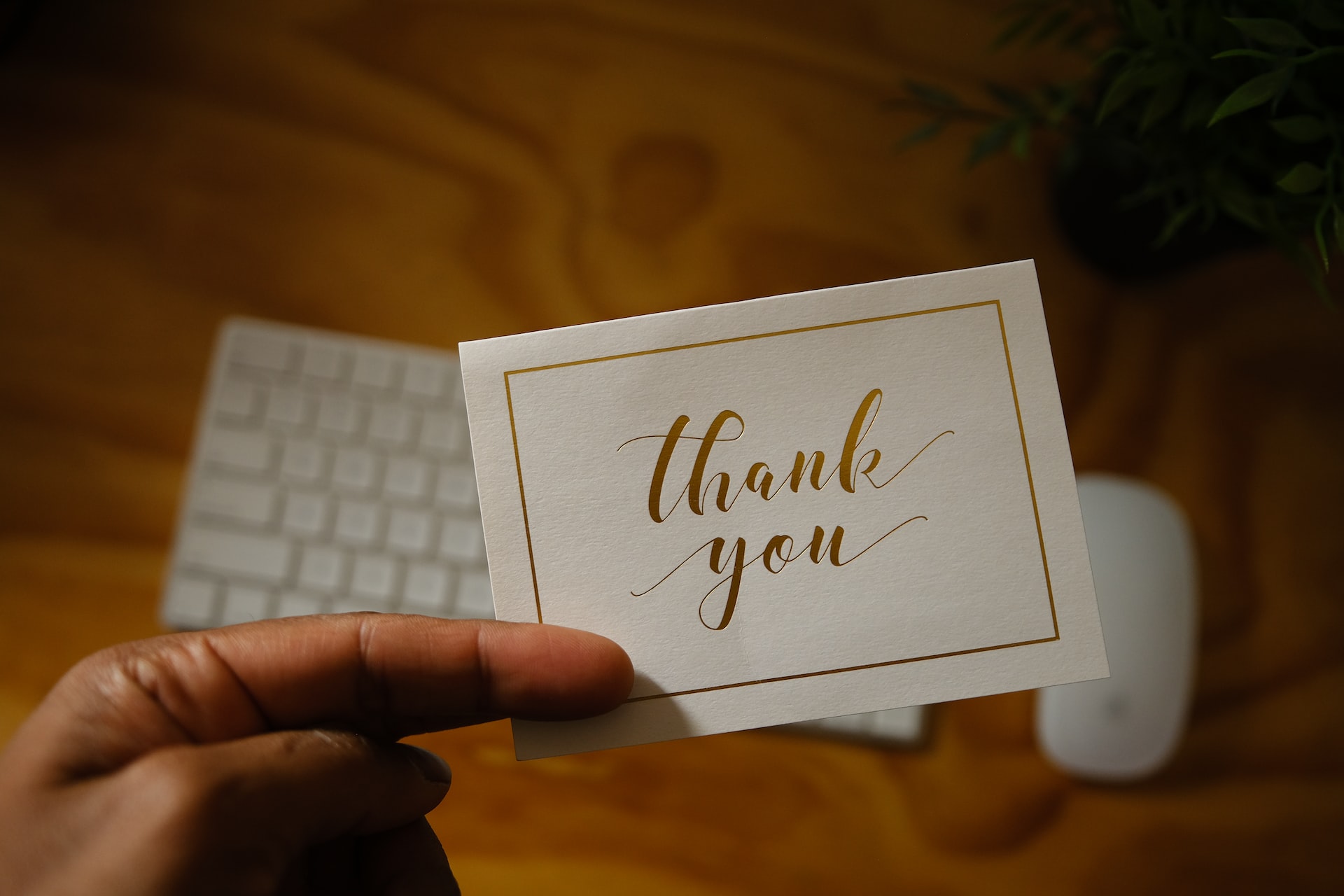 hand holding a thank you card over a keyboard