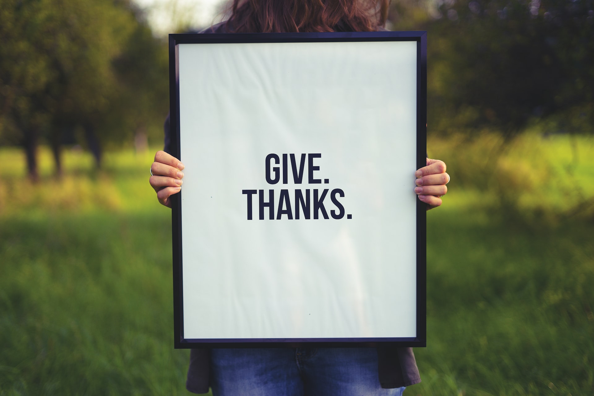 person holding up poster that says give thanks